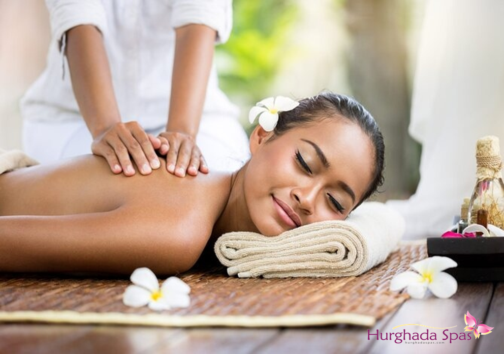 Relaxed woman enjoying a soothing back massage with flowers and spa oils at Belleza Spa Hurghada.