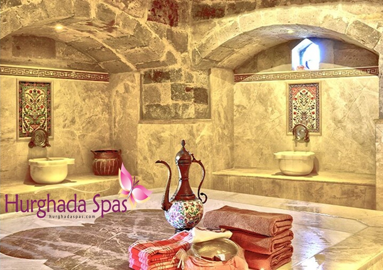 Unveiling the Egyptos Royal Program Traditional Turkish Hamam interior at Egyptos Spa Hurghada featuring marble architecture, stone arches, and copper water vessels.