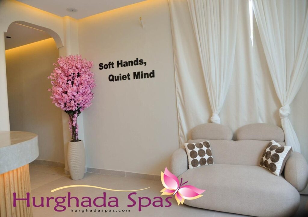 The elegant reception area of Soul Spa Hurghada featuring a plush beige lounge, a decorative pink cherry blossom tree, and the "Soft Hands, Quiet Mind" motto on the wall.
