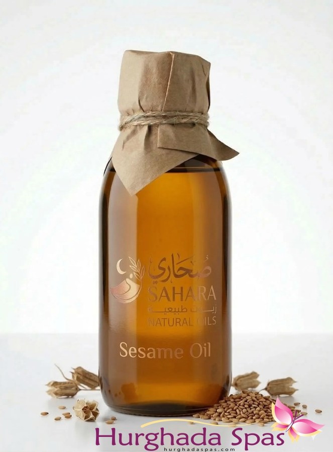 Amber glass bottle of Sahara Natural Oils Sesame Oil Benefits for Skin and Hair Care on a white background with sesame seeds