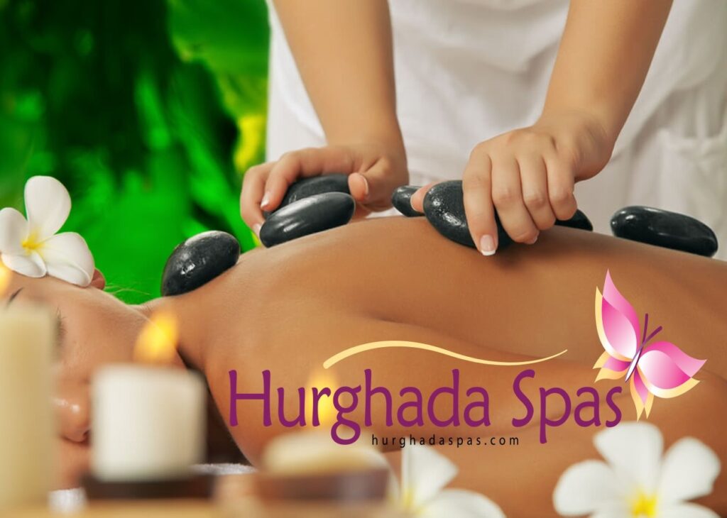 A woman receiving a luxury hot stone massage at Egyptos Spa in Hurghada with heated basalt stones placed along her back.